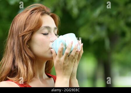 Relaxed woman drinking coffee from mug in a park Stock Photo