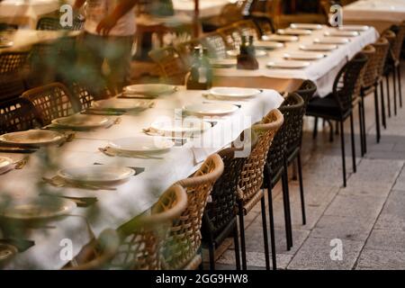 Served tables with white cloth in the restaurant outdoors ready for dinner Stock Photo