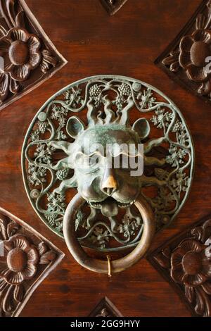 Vintage ancient door knob as lion head made from bronze on wooden surface Stock Photo