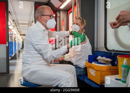 30 August 2021, Berlin: Christian Gravert, chief medical officer of Deutsche Bahn, vaccinates a woman in a special train of the S-Bahn, in which vaccinations with the vaccine of the manufacturer Johnson & Johnson are offered. Photo: Christophe Gateau/dpa Stock Photo