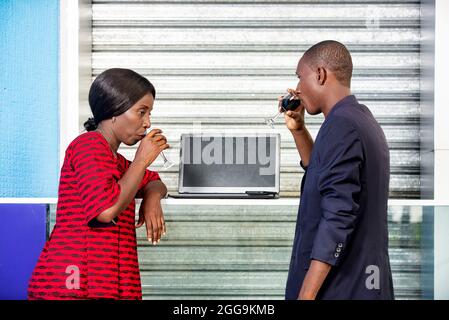 handsome adult businessman and african businesswoman celebrating a victory by drinking a glass of red wine on the street Stock Photo