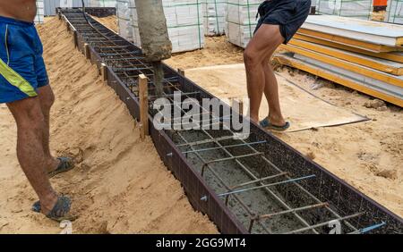 Pouring cement or concrete with automatic pump, construction site with reinforced grillage foundation, start of new house building construction. Stock Photo