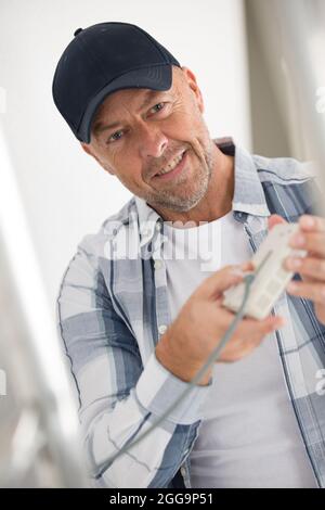 laughing man holding electrical cables Stock Photo