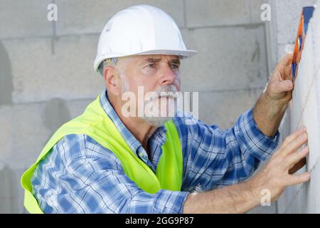 senior male worker measuring wall Stock Photo