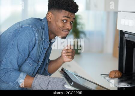 man is removing a burnt cake from the oven Stock Photo