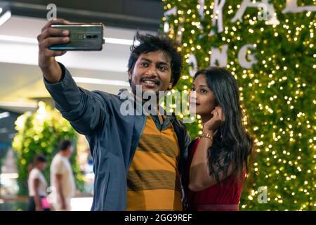 a couple of lovers of Indian nationality take selfies near the Christmas tree on the eve of Christmas in Phuket. street street photography, real life Stock Photo