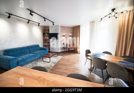 Kitchen studio and living room with cozy blue sofa and stylish modern furniture with beautiful lamps. Concept of interior modern kitchen studio. Stock Photo