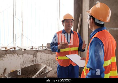 Smiling builder reporting on work that was done in house that is being remodeled when talking to contractor Stock Photo