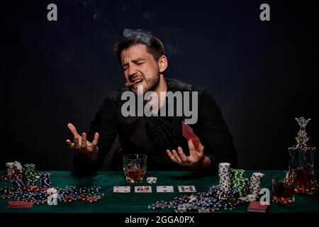 Bearded casino player man playing poker on green table Stock Photo