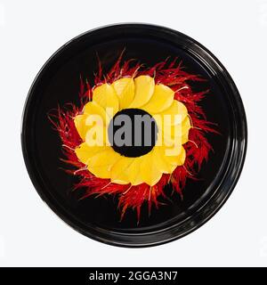 Floating floral art red and yellow fall leaves in a round black vase isolated on white background Stock Photo