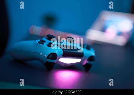 Gaming controller laying on table. Close-up of gamepad in low light room. Selective focus. Professional computer game playing, esport business and onl Stock Photo