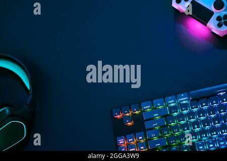 Top down view of backlighted gaming accessories laying on dark desk. Professional computer game playing, esport business and online world concept. Stock Photo