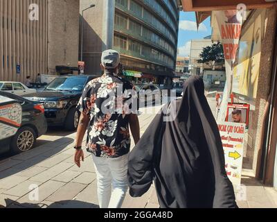 Man in sportswear and woman in hijab walking in Anafartalar Street in the Ulus district in Ankara, Turkey. Stock Photo