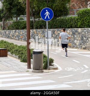 sign of a pedestrian street next to a bike path on the waterfront of a seaside town whit young runner Stock Photo