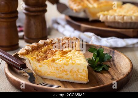 Closeup of a slice of cheese quiche on a wooden plate Stock Photo