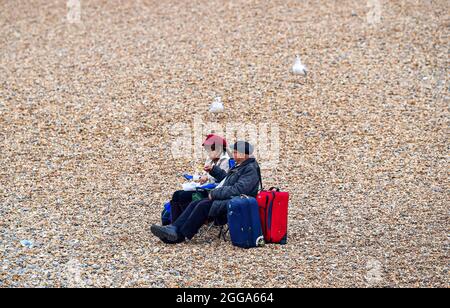 Brighton UK 30th August 2021 -  Visitors on Brighton beach and seafront despite the cool and overcast August bank holiday weather .  : Credit Simon Dack / Alamy Live News Stock Photo