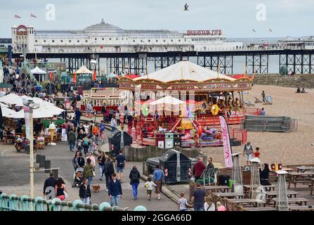 Brighton UK 30th August 2021 - Visitors on Brighton seafront near the pier despite the overcast August bank holiday weather .  : Credit Simon Dack / Alamy Live News Stock Photo