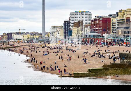 Brighton UK 30th August 2021 -  Visitors on Brighton beach and seafront despite the cool and overcast August bank holiday weather .  : Credit Simon Dack / Alamy Live News Stock Photo