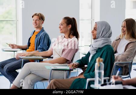 Group of multiethnic university students sitting in classroom indoors, studying. Stock Photo