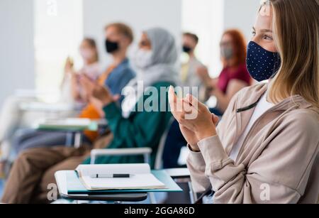 University students clapping in classroom indoors, coronavirus and back to normal concept. Stock Photo