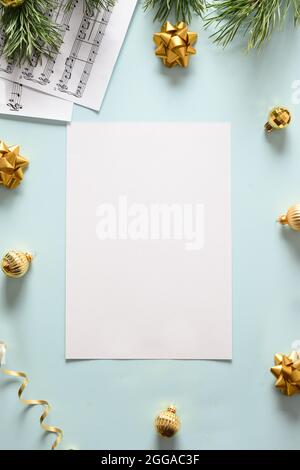 Music sheets for Christmas Carols and sings decorated golden balls on a blue background. View from above. Vertical format. Stock Photo