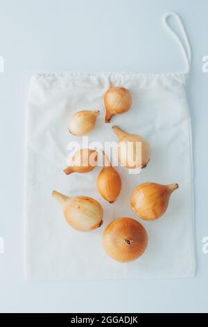 Round onions on reusable eco bags. Creative concept of eco friendly bags. Plastic free concept. Flat lay. Top View. Stock Photo