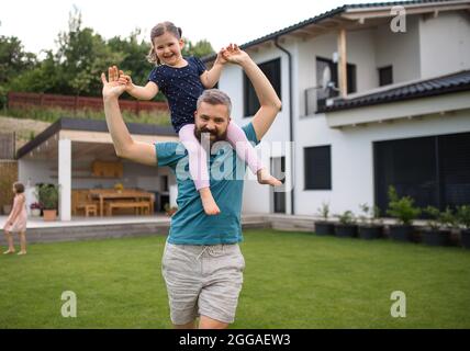 Father with daughters playing outdoors in the backyard, running. Stock Photo