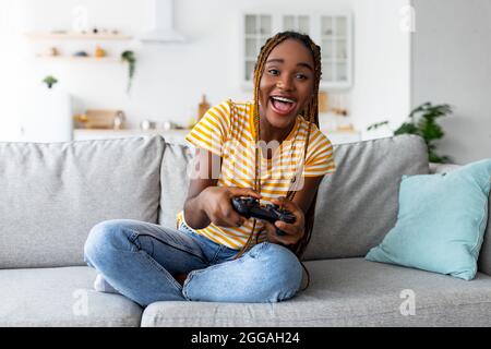 Happy young woman playing video game at home - a Royalty Free