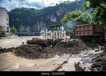 (210830) -- CHONGQING, Aug. 30, 2021 (Xinhua) -- Workers remove mud after a flood in Wuxi County of Chongqing, southwest China, Aug. 30, 2021. Heavy rain has led to the flooding of four rivers in southwest China's Chongqing Municipality, and more than 2,000 people have been evacuated, according to Chongqing's flood control and drought relief headquarters. In Wuxi County, more than 260 shops were flooded due to constant rain. Local public security and emergency departments have jointly established rescue teams to help shop owners transfer materials and evacuate people who are trapped to safe Stock Photo