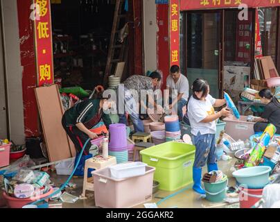 (210830) -- CHONGQING, Aug. 30, 2021 (Xinhua) -- Shop owners clean items after a flood in Wuxi County of Chongqing, southwest China, Aug. 30, 2021. Heavy rain has led to the flooding of four rivers in southwest China's Chongqing Municipality, and more than 2,000 people have been evacuated, according to Chongqing's flood control and drought relief headquarters. In Wuxi County, more than 260 shops were flooded due to constant rain. Local public security and emergency departments have jointly established rescue teams to help shop owners transfer materials and evacuate people who are trapped to Stock Photo