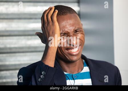 young businessman standing in suit outdoors suffering from headache. Stock Photo