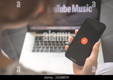 Kharkov, Ukraine - August 25, 2021: Youtube Music app logo on the mobile phone screen. Woman using Youtube Music application and holding smartphone Stock Photo