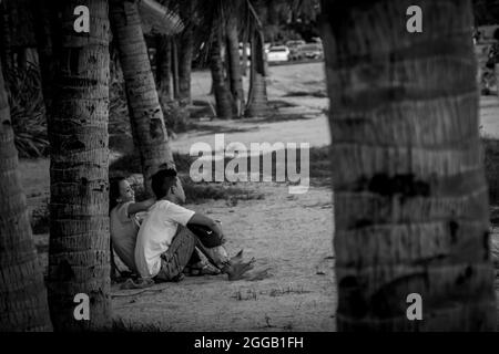 SUBIC, PHILIPPINES - Aug 01, 2017: A grayscale view of a Filipino couple dating sitting at the beach of SMBA in Subic City, Philippines Stock Photo