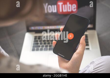 Kharkov, Ukraine - August 25, 2021: Youtube Music app logo on the mobile phone screen. Woman using Youtube Music application and holding smartphone Stock Photo