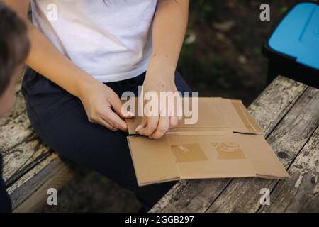 Close-up woman preparing cardboard for recycling. Female sorting garbage at home. Concept of recycling Stock Photo