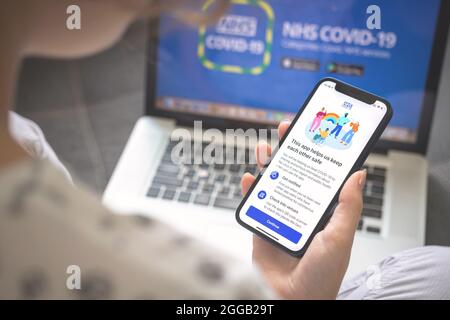 Kharkov, Ukraine - August 25, 2021: Woman using NHS COVID-19 coronavirus test app and holding smartphone, stock image Stock Photo