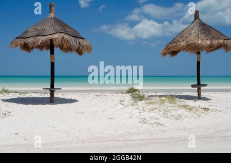 A tropical beach with two straw umbrellas. Vacation concept tropical beach island of Holbox, Mexico Stock Photo