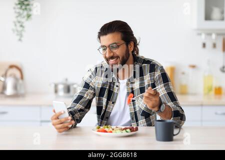 Handsome arab man using cellphone while having breakfast Stock Photo