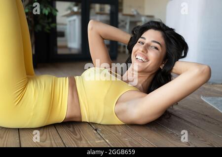 Athletic young Caucasian woman doing abs exercises during her home workout Stock Photo