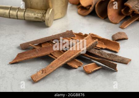 Heap of dried Cinnamon bark close up in front of a traditional mortar and pestle ready to ground Stock Photo