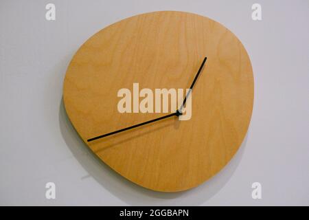 Wooden clock on the white wall in minimalistic design. Interior design. Home decor Stock Photo