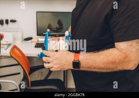 Selective focus on the hands of a man holding a dental articulator in a laboratory Stock Photo