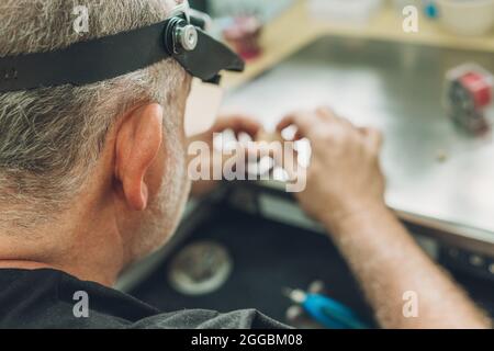 Selective focus on the head of a man working in a dental laboratory Stock Photo