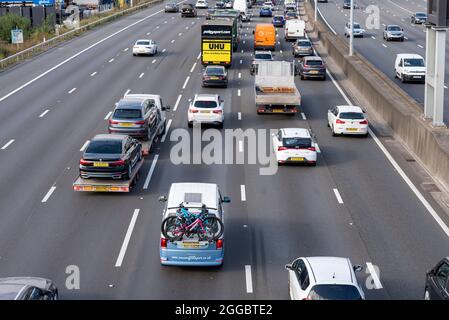 Section of M25 motorway in Longford near Heathrow Airport, UK, busy with traffic on a Bank Holiday August summer weekend. Campervan with bicycles Stock Photo