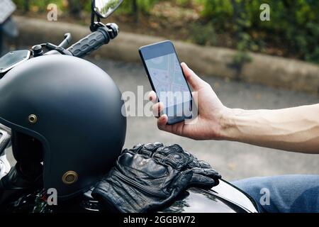 Close-up image of motorcyclist checking map application on smartphone when searching address of customer Stock Photo