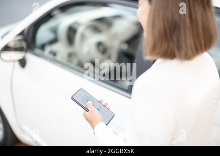 Woman control car alarm with mobile phone Stock Photo