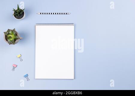 Open spiral notebook with blank white page, pencil and succulents on light gray desk background. Top view, copy space for text Stock Photo