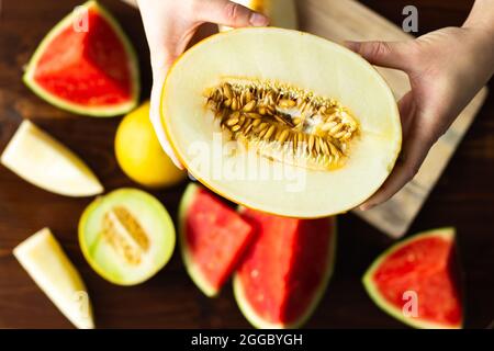 Top view of hands holding cut honeydew melon with seeds; variety of melon Stock Photo