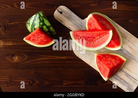 Top view of ripe cut watermelon on wooden cutting board and rustic wood with copy space; summer fruit Stock Photo