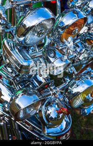 Many shiny chrome polished headlights on the front of a scooter motorbike Stock Photo